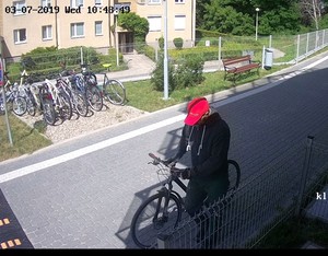 Zdjęcie poglądowe, przedstawiające mężczyznę prowadzącego rower. Mężczyzna ma na sobie ciemne ubranie.