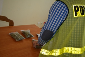 Zdjęcie poglądowe, przedstawiające policjanta zabezpieczającego narkotyki.
