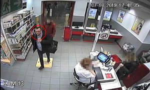 Zdjęcie poglądowe, przedstawiające mężczyznę podejrzewanego o kradzież perfum. Mężczyzna jest w sklepie, idzie z dużą torbą na lewym ramieniu. Przy kasie siedzi ekspedientka.