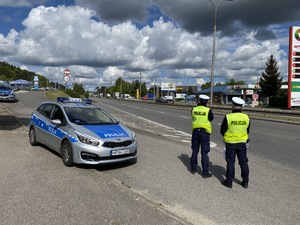 Dwóch policjantów prowadzących działania prewencyjne na drodze w ramach akcji „Bezpieczne wakacje 2020”.