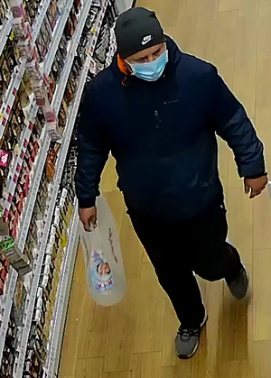 Zdjęcie przedstawiające mężczyznę, znajdującego się w sklepie. Mężczyzna trzyma w ręku reklamówkę.