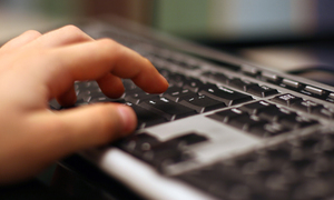 Zdjęcie poglądowe, przedstawiające klawiaturę od komputera, na klawiaturze dłoń.