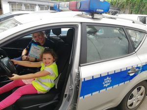 Zdjęcie przedstawiające policjantkę ze swoją córką, obie są w radiowozie policyjnym.