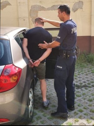 Zdjęcie przedstawiające policjanta z zatrzymanym mężczyzną