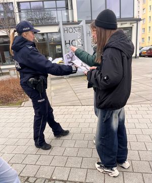 Zdjęcie przedstawiające policjantkę, która rozdaje młodzieży ulotki