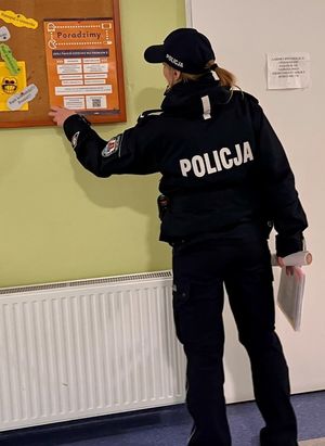 Zdjęcie przedstawiające policjantkę, która zostawia ulotki profilaktyczne