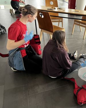 Zdjęcie przedstawiające siedzącą na podłodze pozorantkę i uczennicę wykonującą ćwiczenie.