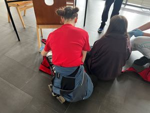 Zdjęcie przedstawiające pozorantkę siedzącą na podłodze i uczennicę, która wykonuje zadanie.