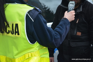 Zdjęcie poglądowe, na którym policjantka stoi przed mężczyzną i przeprowadza mu badanie alkotestem na zawartość alkoholu w organizmie.