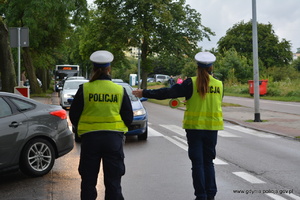 Zdjęcie poglądowe, przedstawiające dwie policjantki ruchu drogowego, które kierują ruchem pojazdów. Jedna z nich daje kierowcom sygnał, nakazujący skręcić w prawo.