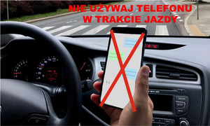 Zdjęcie poglądowe, przedstawiające telefon w dłoni osoby, prowadzącej samochód. Ekran telefonu jest przekreślony znakiem X. Nagranie przedstawia opisane zdjęcie, a na końcu pojawia się napis: Nie używaj telefonu w trakcie jazdy.