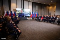 Zdjęcie poglądowe, przedstawiające policjantów siedzących w auli i oglądających prezentację. Na ekranie widać policjanta, który opowiada o swoim bohaterskim czynie.