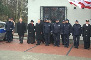 Zdjęcie poglądowe, przedstawiające Komendanta Wojewódzkiego Policji w Gdańsku, Komendanta Miejskiego Policji w Gdyni, Prezydenta Miasta Gdyni, księdza kapelana oraz innych funkcjonariuszy i zaproszonych gości. Wszyscy stoją przed budynkiem nowego komisariatu podczas uroczystego otwarcia.