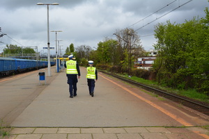 Zdjęcie przedstawiające policjantkę i policjanta, którzy idą po peronie kolejowym.