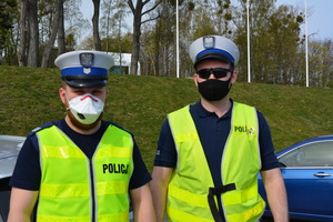 Zdjęcie przedstawiające dwóch policjantów ruchu drogowego. Policjanci mają na sobie maseczki ochronne.