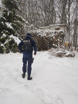 Zdjęcie przedstawiające umundurowanego policjanta przy pustostanie