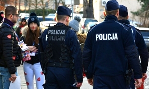 Zdjęcie przedstawiające policjantów na tle kwestionariuszy z Wielkiej Orkiestry Świątecznej Pomocy