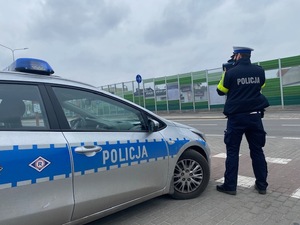 Zdjęcie przedstawiające policjanta, który sprawdza prędkość nadjeżdżającym samochodom.