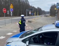 Zdjęcie przedstawiające policjanta podczas pracy. zdjęcie wykonane m. in. na tle drogi rowerowej.