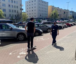 Zdjęcie przedstawiające mężczyznę jadącego na deskorolce oraz policjantkę.