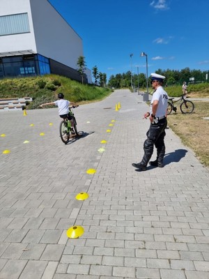 Zdjęcie przedstawiające policjanta podczas przeprowadzania egzaminu na kartę rowerową