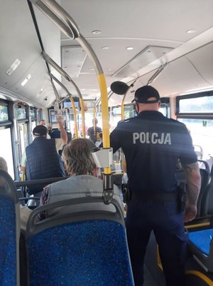 Policjanci kontrolują przestrzeganie obostrzeń COVID19 w autobusach komunikacji miejskiej.