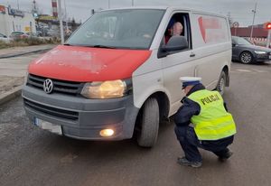 Zdjęcie przedstawiające policjanta sprawdzającego stan opon