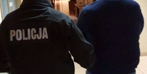 Zdjęcie przedstawiające policjanta prowadzącego zatrzymanego mężczyznę