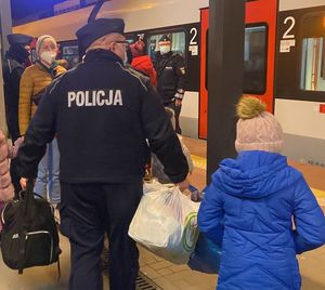 Zdjęcie przedstawiające policjantów pomagających uchodźcom z Ukrainy