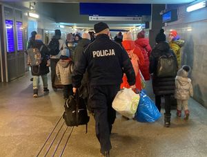 Zdjęcie przedstawiające policjantów pomagających uchodźcom z Ukrainy