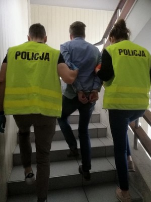 Zdjęcie przedstawiające policjantów prowadzących zatrzymanego mężczyznę