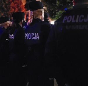 Zdjęcie przedstawiające stojących tyłem policjantów