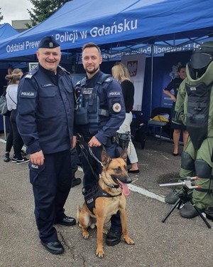 Zdjęcie przedstawiające Komendanta Wojewódzkiego Policji z przewodnikiem psa oraz psem służbowym