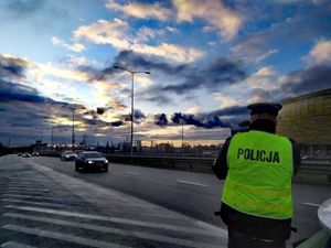 Zdjęcie przedstawiające policjanta mierzącego prędkość pojazdów