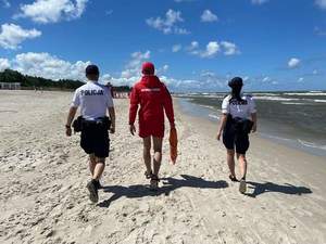 Zdjęcie przedstawiające policjantów i ratownika na plaży