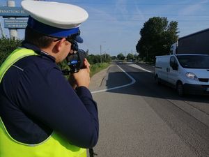 Zdjęcie przedstawiające policjanta mierzącego prędkość pojazdów