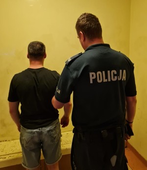 Zdjęcie przedstawiające policjanta prowadzącego zatrzymanego mężczyznę