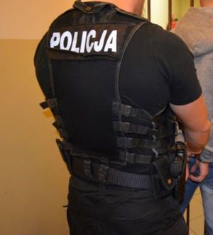 Zdjęcie poglądowe, przedstawiające policjanta zapinającego kajdanki zatrzymanemu