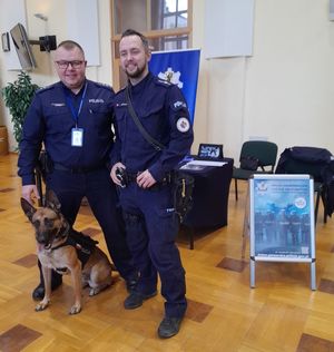 Zdjęcie z targów pracy służb mundurowych, przedstawiające policjantów z psem służbowym