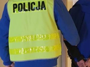 Zdjęcie poglądowe, przedstawiające policjanta prowadzącego zatrzymaną osobę