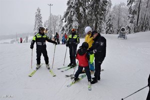 Zdjęcie przedstawiające policjanta z dorosłymi i dzieckiem na stoku narciarskim