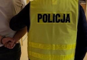 Zdjęcie poglądowe, przedstawiające policjanta prowadzącego zatrzymanego mężczyznę