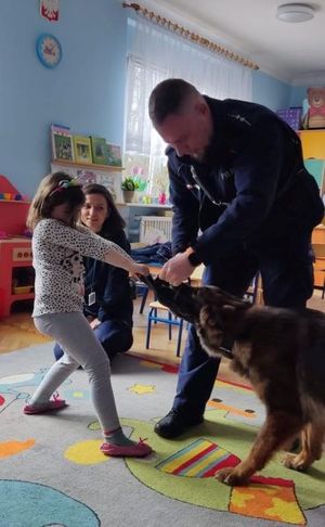 Zdjęcie przedstawiające policjantów, psa służbowego oraz przedszkolaka