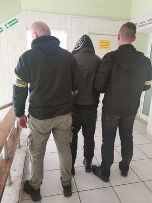 Zdjęcie przedstawiające policjantów prowadzących zatrzymanego mężczyznę