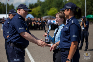 Zdjęcie przedstawiające Komendanta Wojewódzkiego Policji w Gdańsku, który wręcza uczennicy klasy o profilu policyjnym puchar. Na zdjęciu obok licealistki stoi policjantka.