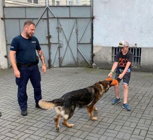 Zdjęcie przedstawiające policjanta z psem służbowym oraz ucznia