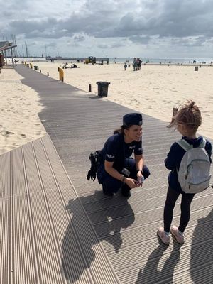 Zdjęcie przedstawiające policjantkę na plaży, podczas rozmowy z dzieckiem