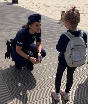 Policjantka rozmawia na plaży z dzieckiem