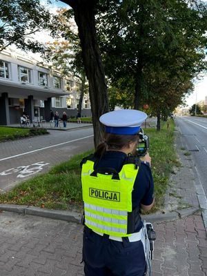 Zdjęcie przedstawiające policjantkę, która mierzy prędkość w okolicy szkoły