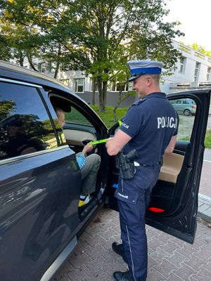 Zdjęcie przedstawiające policjanta, który rozmawia z dzieckiem na temat bezpieczeństwa w ruchu drogowym